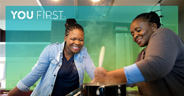 Two women smiling while cooking