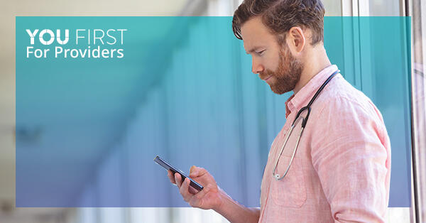 Health care provider looking at mobile phone, with You First logo